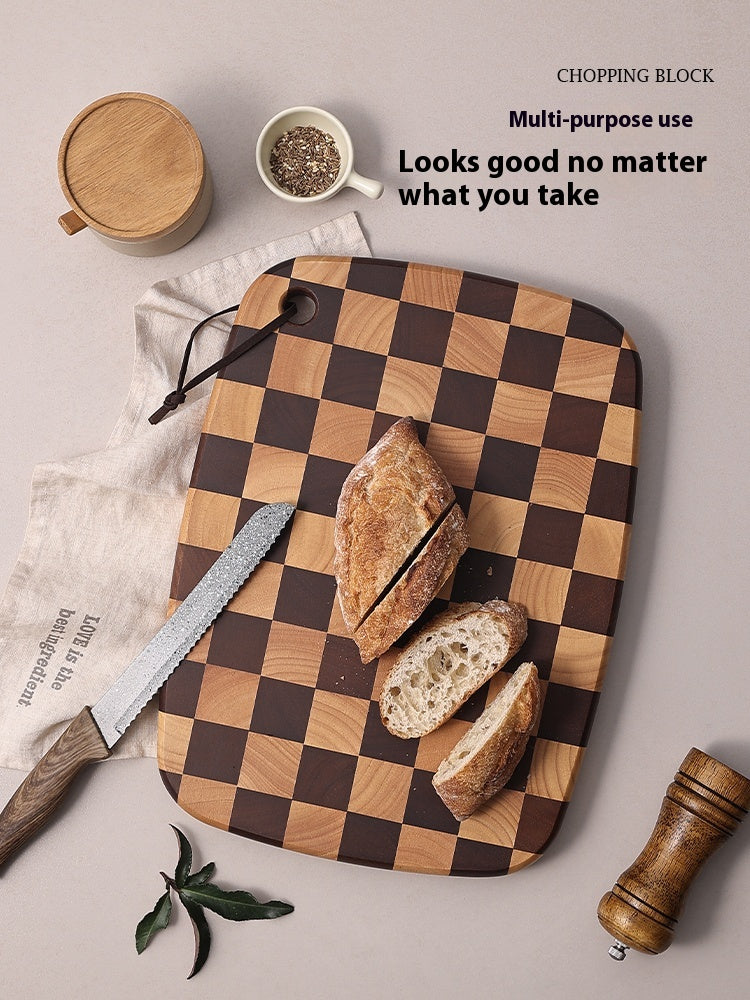 Checkered wooden chopping block with bread slices, knife, and kitchen items on a light background.