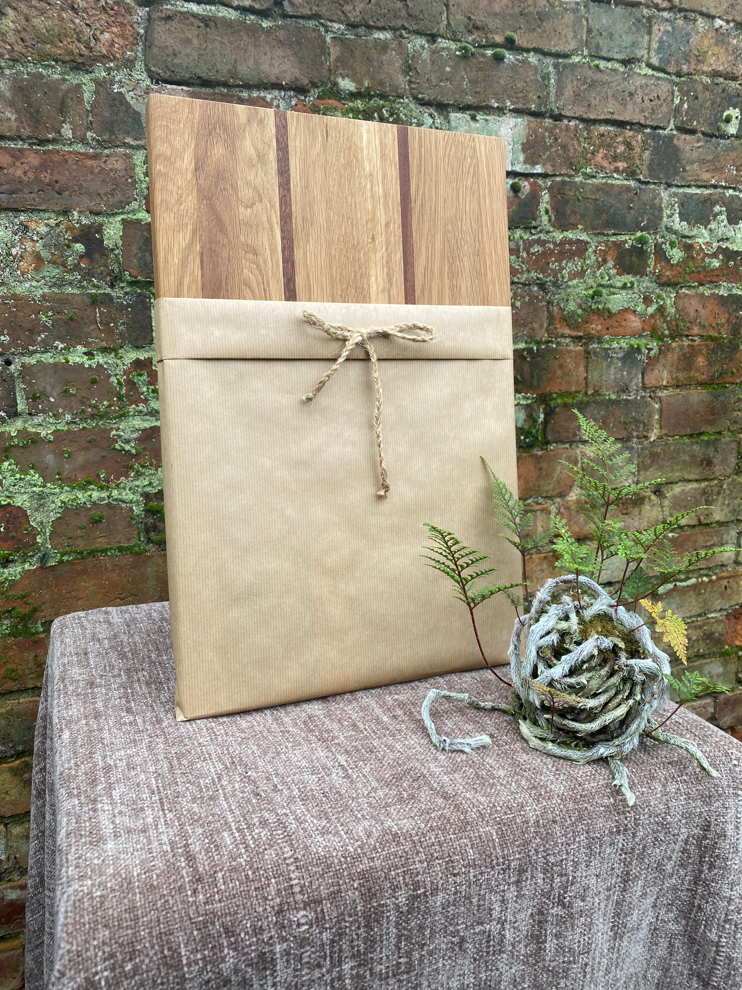 Wooden cutting board and wrapped package on a textured surface with a brick wall background