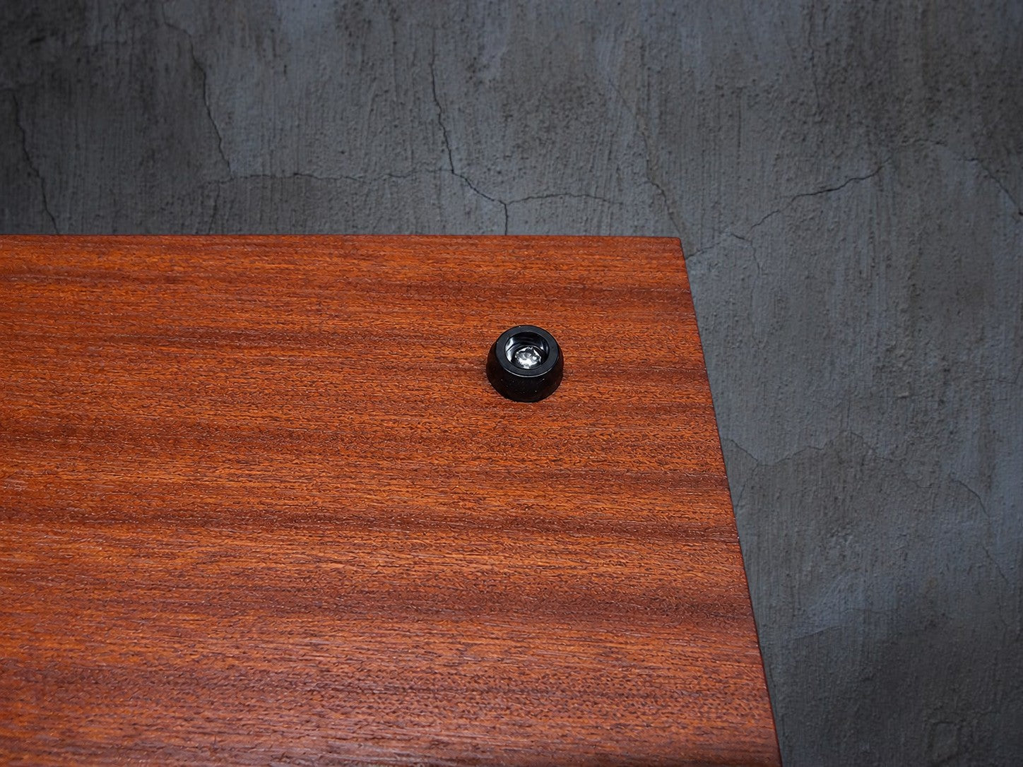 A close-up of a Rubber Board Foot on a reddish-brown wood-grain Chopping Board, positioned over a blue cutting mat.